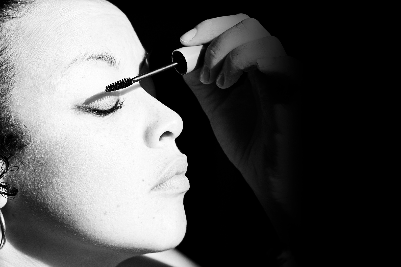 Portrait de femme en noir et blanc en train de se maquiller
