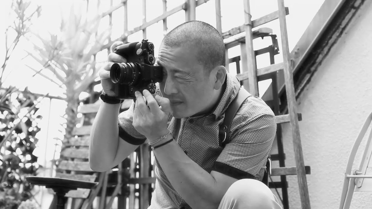 homme concentré tenant un appareil photo et prenant une photo en extérieur, en noir et blanc